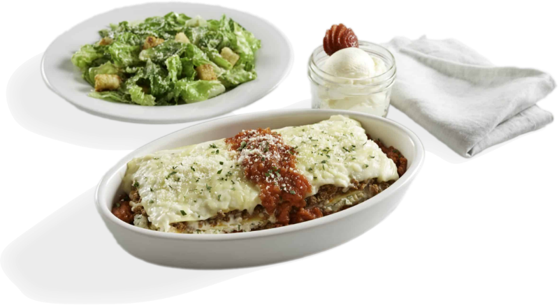 Lasagna in a white dish with a side salad